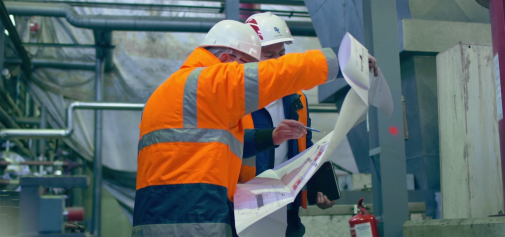 Employés du Groupe OTE en EPI sur chantier consultant une carte.